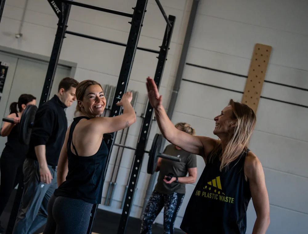 Zwei Athletinnen klatschen sich nach dem gemeinsamen Training lachend ab